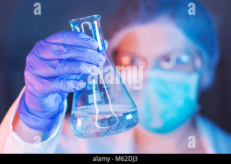 Scientist working with chemicals in laboratory, female researcher analyzing liquid reagent in lab glassware Stock Photo