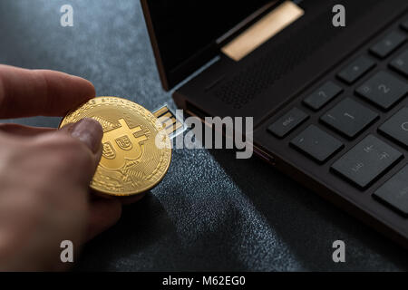 A hand plugging in a Bitcoin thumb drive into windows laptop Stock Photo