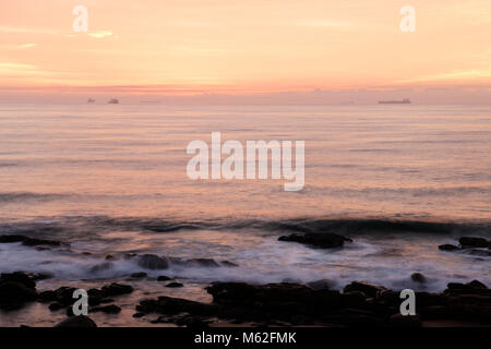 Durban, KwaZulu-Natal, South Africa, moody beach scene of ships silhouette on horizon, breaking dawn, Umhlanga Rocks beach, landscape Stock Photo