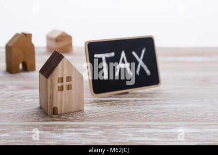 Different model of houses on wooden table with tax sign for property tax concept Stock Photo