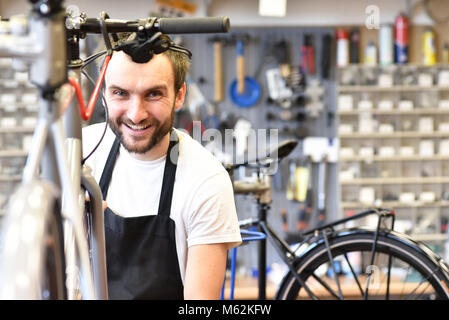 portrait of a friendly and competent bicycle mechanic in a workshop repairs a bike Stock Photo