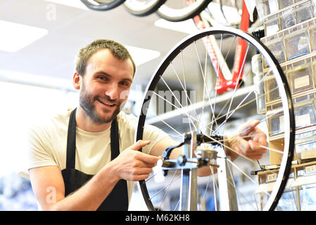 friendly and competent bicycle mechanic in a workshop repairs a bike Stock Photo