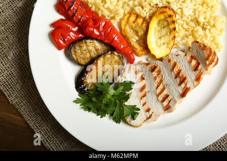 Grilled chicken with slices, with vegetables, bulgur on a white plate, decorated with parsley. Low-calorie, dietary food for a healthy lifestyle. View Stock Photo