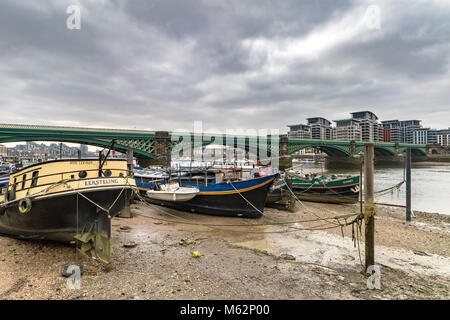 Boats moored at low tide on The River Thames near  Battersea Railway Bridge , Battersea , London United Kingdom Stock Photo