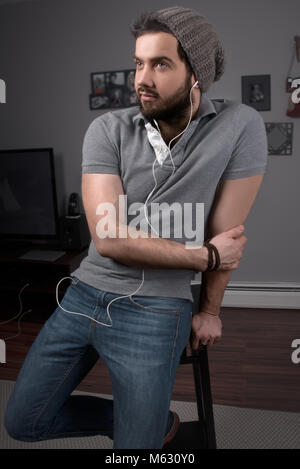 guy with a beard with headphones listens music,Young and smiling man relaxing at home is listening music Stock Photo