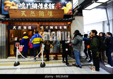 Customers standing in line at a famous traditional Japanese cookie shop in the  busy commercial center in Tenjin, Fukuoka, Japan. Stock Photo