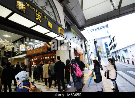 Customers standing in line at a famous traditional Japanese cookie shop in the  busy commercial center in Tenjin, Fukuoka, Japan. Stock Photo