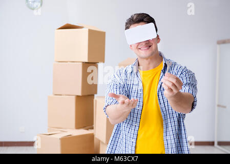 Young man wearing VR glasses moving in new apartment Stock Photo