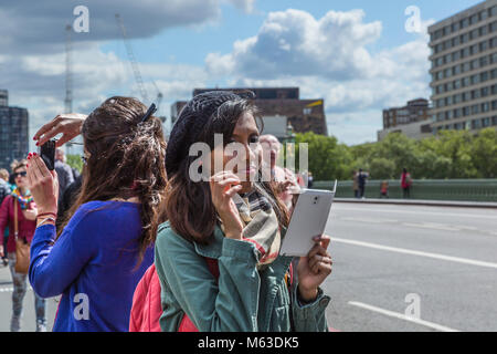 Tourists on Westminster Bridge, London taking pictures with iPad and cameras. Stock Photo