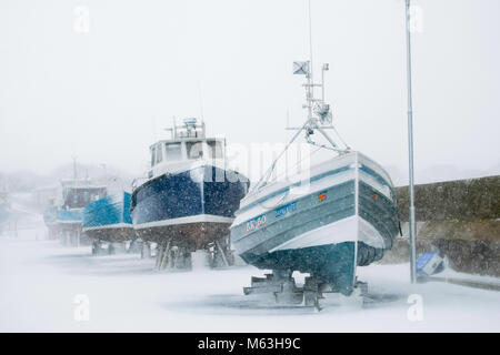 Boats on the harbour at Seahouses in winter snow conditions Stock Photo
