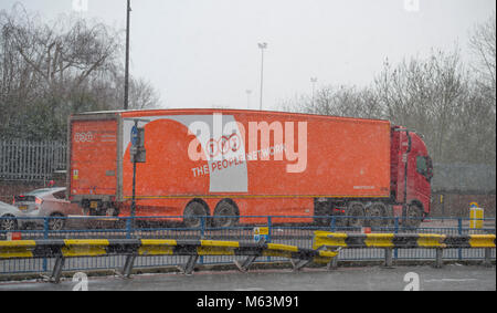 Merton, London, UK. 28 February 2018. After a day largely of strong winter sunshine a freshening east wind drives in snow in south west London to coincide with start of evening rush hour. Early evening traffic passes through Morden town centre in a snow shower. Credit: Malcolm Park/Alamy Live News. Stock Photo