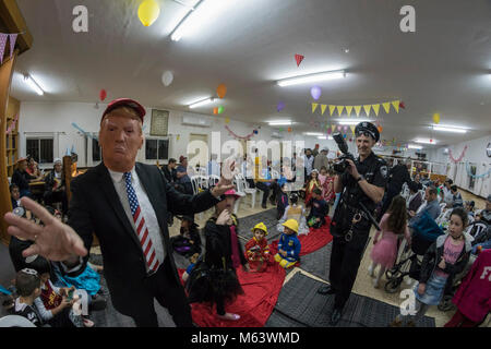 Elkana, Israel. 28th Feb, 2018. Purim holiday celebrations, Elkana, Israel. February 28th, 2018. A man with a Trump Mask and other people in costumes celebrate the Jewish holiday of Purim. In this holiday Jews traditionaly dress in costumes, read the scroll of Esther, a story about an anti-jewish failed plot in ancient Persia, and make a racket whenever the name of Haman, the main antagonist, is mentioned. Credit: Yagil Henkin/Alamy Live News Stock Photo