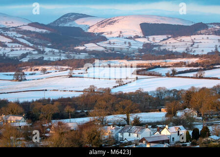 Flintshire, Wales, UK , UK Weather:  The Beast form the East continues to wreak havoc in many areas in the UK with snow and freezing temperatures. A frozen snow covered landscape in rural Flintshire with Moel Arthur and the Clwydian Range in the distance as the sun rises over the area with Storm Emma arrivng bringing more snow Stock Photo