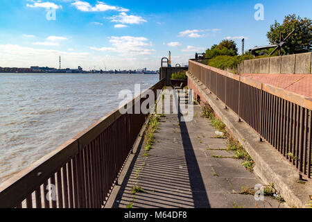 River Thames flood defences and footpath at North Woolwich, London in the distance is the Thames Barrier Stock Photo