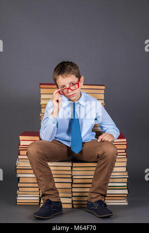 Boy leader sitting on the throne from books, education funny idea Stock Photo