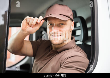 Portrait Of A Happy Young Delivery Man Sitting Inside Van Stock Photo