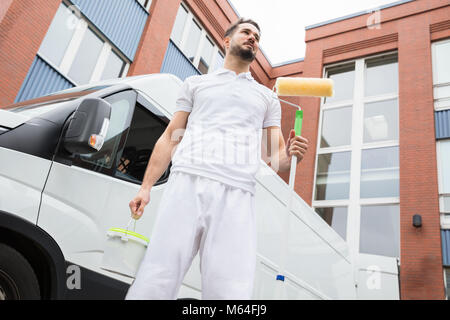 Portrait Of A Young Male Painter Standing With Paint Roller Stock Photo