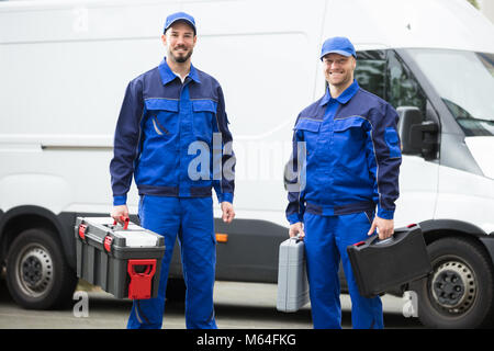 Portrait Of A Happy Young Male Worker Holding Toolbox Stock Photo