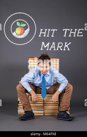 Hit the mark. Funny education concept with happy boy sitting on a throne from books Stock Photo
