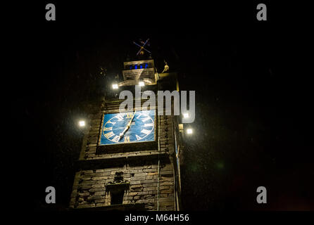 Looking up at 17th century Tolbooth Steeple, Glasgow Cross, Glasgow, Scotland, UK. Lights capture snow flurries in the dark night sky in Winter Stock Photo