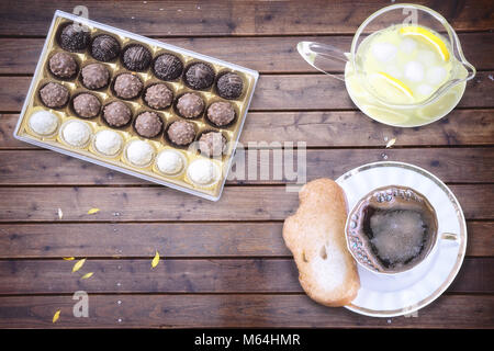 On the surface of the wooden table coffee Cup with croutons, chocolates, lemon with ice. Stock Photo