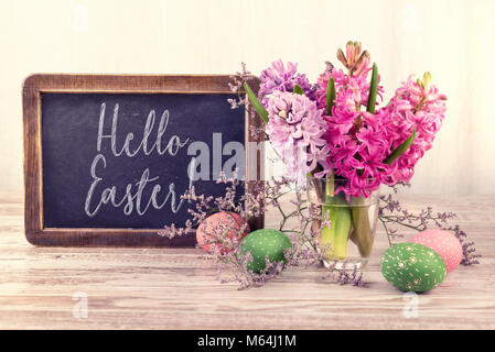 Chalk board and bunch of hyacinth flowers on neutral background, text 'Happy Easter' on the blackboard. Stock Photo