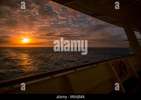 Sunset over the Atlantic ocean from the stern of a cruise ship with clouds Stock Photo