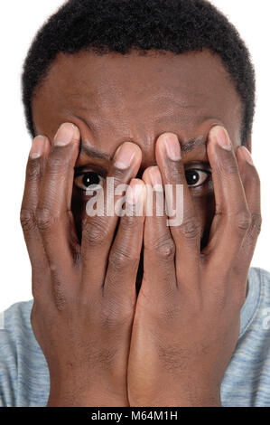 A young African American man in a close up image holding his hands over his face, looking trough, isolated for white background Stock Photo