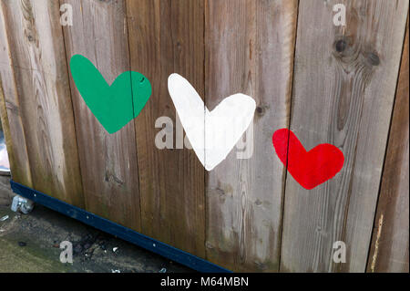 Painted red green and white hearts on wooden fence Stock Photo