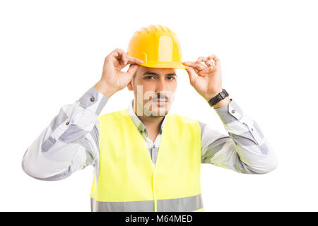 Constructor or builder fixing his protection yellow hard hat isolated on white background Stock Photo