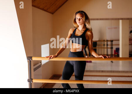 woman dancer posing near barre in ballet studio Stock Photo