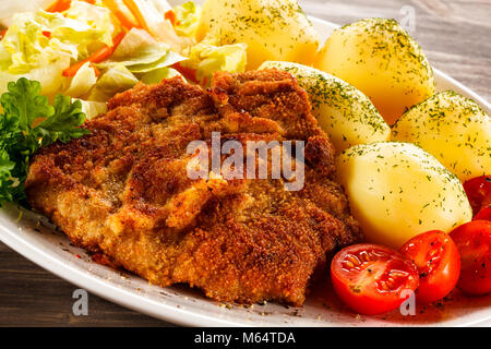 Fried pork chop with potatoes on wooden table Stock Photo