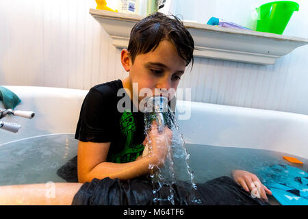 Twin Caucasian Brothers Play in Their Water Filled Bathtub Together With Their Clothes On Stock Photo