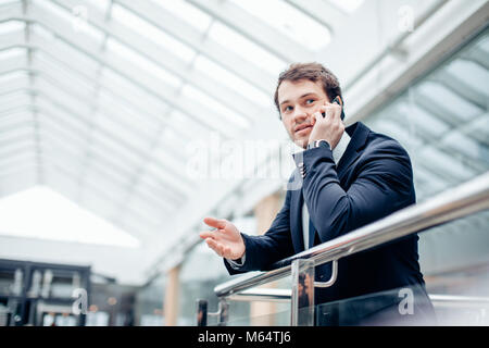 Business man walking while talking on mobile phone on his way to work Stock Photo