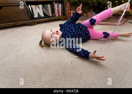 A Caucasian Girl Plays With A New Years Eve Balloon in Her Suburban Home Living Room Stock Photo