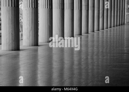 Line of greek columns with reflections on a super shiny floor and no people in monochrome Stock Photo