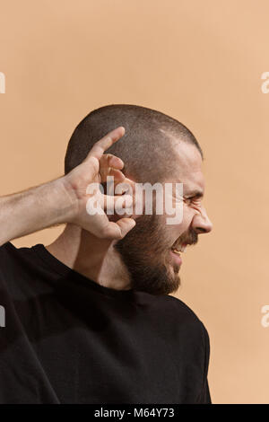 The Ear ache. The sad man with headache or pain on a pastel studio background. Stock Photo