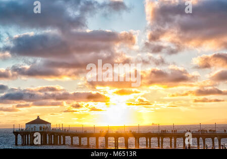 Sunset on Manhattan beach pier, Los Angeles, in a summer day with the sky full of clouds. Background with an American pier full of people Stock Photo