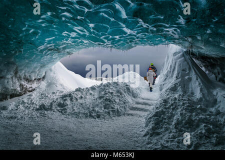 Tourists in The Crystal Cave, Breidamerkurjokull Glacier, Iceland. Emerald Blue Ice and Ash is part of Breidamerkurjokull. Stock Photo