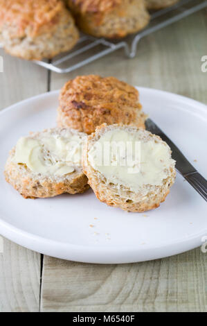 Freshly baked cheese scones spread with butter. Stock Photo