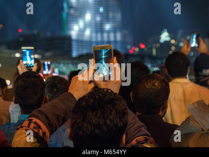 31th December 2017 - Dubai, UAE. Men records laser show on his smart phone at Burj Khalifa. People celebrating new year. Stock Photo