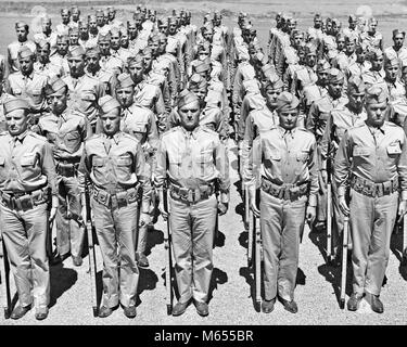 1940s ROWS OF AMERICAN WORLD WAR II SOLDIERS STANDING AT ATTENTION WITH RIFLES LOOKING AT CAMERA - a2433 HAR001 HARS WORLD WAR WORLD WAR TWO FORMATION ROWS TROOPS UNIFORMS RIFLES LARGE GROUP OF PEOPLE FIREARM FIREARMS KHAKI MALES MID-ADULT MAN WEAPONS YOUNG ADULT MAN B&W BLACK AND WHITE CAUCASIAN ETHNICITY LOOKING AT CAMERA OCCUPATIONS OLD FASHIONED PERSONS RANK RANK AND FILE RECRUITS REGIMENT STANDING AT Stock Photo