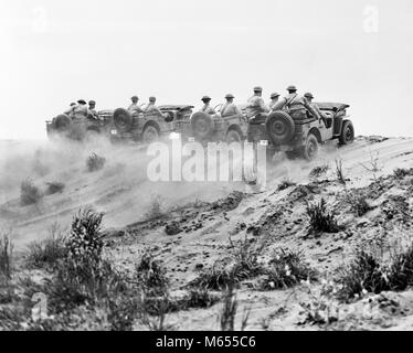 1940s ARMY SOLDIERS RIDING JEEPS IN FORMATION GOING UP A DUSTY HILL - a2739 HAR001 HARS EXCITEMENT LOW ANGLE WORLD WARS WORLD WAR WORLD WAR TWO FORMATION UNIFORMS DUNE UTILITY VEHICLES GROUP OF PEOPLE HELMETS DUSTY KHAKI MALES SAND DUNE 1/4 TON 4X4 B&W BLACK AND WHITE FORD GPW FOUR-WHEEL DRIVE JEEPS MP MULTIPURPOSE OLD FASHIONED PERSONS WILLYS WILLYS-OVERLAND MOTORS Stock Photo