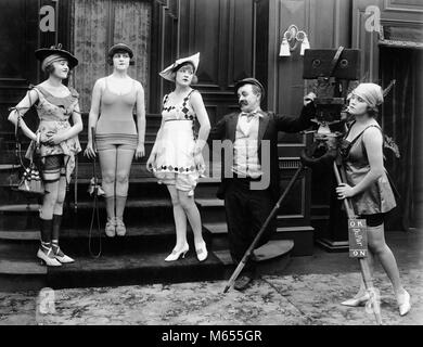 1910s COMIC PHOTOGRAPHER WITH MODELS IN SKIMPY BATHING COSTUMES SILENT MOVIE STILL - asm00721 CAM001 HARS 18-19 YEARS POSING SILENT 1910s COMEDY SILENT MOVIE SMALL GROUP OF PEOPLE BATHING SUIT SILENT MOVIE STILL MALES MID-ADULT WOMAN MOVIE CAMERA YOUNG ADULT WOMAN B&W BATHING BEAUTIES BEN TURPIN BLACK AND WHITE CAUCASIAN ETHNICITY HORIZONTAL MACK SENNETT OLD FASHIONED PERSONS SKIMPY STILL ACTRESS Stock Photo