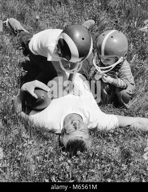 1970s MAN FATHER LYING IN GRASS HOLDING FOOTBALL AFTER BEING TACKLED BY SON AND DAUGHTER - b25063 HAR001 HARS OLD TIME SURPRISE BROTHER OLD FASHION SISTER 1 JUVENILE YARD BALANCE TEAMWORK COMPETITION CAUCASIAN SONS JOY LIFESTYLE FEMALES BROTHERS HEALTHINESS HOME LIFE FULL-LENGTH GROUND HALF-LENGTH PHYSICAL FITNESS DAUGHTERS CARING RISK SIBLINGS CONFIDENCE SISTERS NOSTALGIA FATHERS TOGETHERNESS 25-30 YEARS 30-35 YEARS SUCCESS 5-6 YEARS HAPPINESS WELLNESS STRENGTH RELAXATION AND DADS EXCITEMENT POWERFUL RECREATION AUTHORITY GROWTH SIBLING CONNECTION COOPERATION HELMETS SMALL GROUP OF PEOPLE Stock Photo