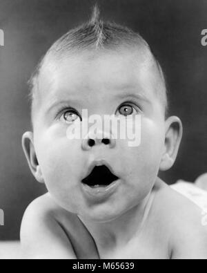 1950s BABY MAKING FUNNY FACE MOUTH OPEN LOOKING UP SHOCK SURPRISE AWE WONDER FACIAL EXPRESSION - b4365 HAR001 HARS LOOKING UP B&W BABY GIRL BLACK AND WHITE CAUCASIAN ETHNICITY MOUTH OPEN OLD FASHIONED Stock Photo