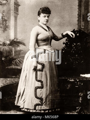 1800s MIDDLE TO LATE 19TH CENTURY PORTRAIT OF WOMAN WITH STERN FACE AND LONG DRESS WITH BUSTLE STANDING LOOKING AT CAMERA - c3082 HAR001 HARS CHARACTERS STERN 1890s FASHIONS 19TH CENTURY TURN OF CENTURY BUSTLE MID-ADULT MID-ADULT WOMAN WAIST B&W BLACK AND WHITE CAUCASIAN ETHNICITY CORSETED LOOKING AT CAMERA OLD FASHIONED PERSONS Stock Photo