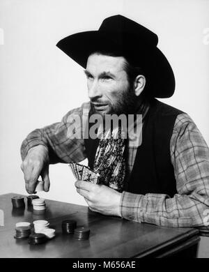 1930s BEARDED MAN COWBOY PLAYING CARDS GAMBLING BETTING POKER CHIPS - c988 HAR001 HARS CHOICE EXCITEMENT LUCKY RECREATION OPPORTUNITY GAMBLE MALES B&W BET BETTING BLACK AND WHITE CAUCASIAN ETHNICITY CHANCE COWBOY HAT GAMBLER GAME OF CHANCE OLD FASHIONED PERSONS POKE Stock Photo