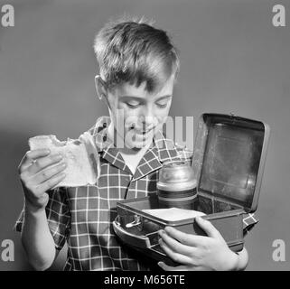 1950s SMILING BOY EATING SANDWICH LOOKING INTO LUNCH BOX WITH THERMOS - f6553 DEB001 HARS COPY SPACE HALF-LENGTH INDOORS NOSTALGIA 10-12 YEARS SCHOOLS GRADE HAPPINESS CHEERFUL DISCOVERY SNACK FOOD CHOICE EXCITEMENT THERMOS GROWTH PRIMARY SMILES JOYFUL NOURISHMENT K-12 GRADE SCHOOL JUVENILES LUNCH BOX MALES PRE-TEEN BOY B&W BLACK AND WHITE CAUCASIAN ETHNICITY LOOKING INTO OLD FASHIONED WHITE BREAD Stock Photo