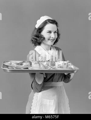 1940s WAITRESS MAID CARRYING TRAY WITH FOOD SERVICE - h889 HAR001 HARS NOSTALGIA EYE CONTACT HAPPINESS CUSTOMER SERVICE SERVANT SMILES JOYFUL SERVER FRIENDLY PLEASANT WAITPERSON YOUNG ADULT WOMAN B&W BLACK AND WHITE CAUCASIAN ETHNICITY LOOKING AT CAMERA OCCUPATIONS OLD FASHIONED PERSONS WAIT STAFF Stock Photo